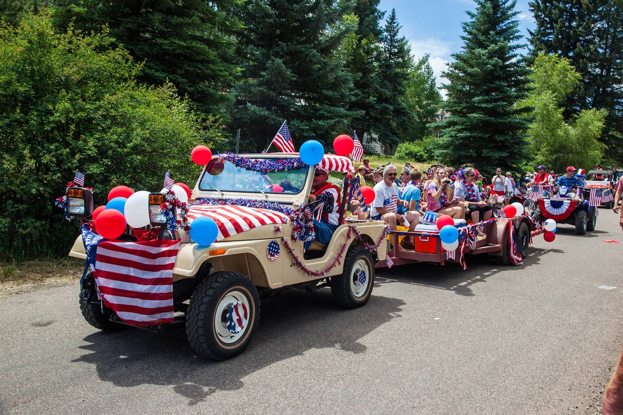 A Tan Jeep Wrangler pulls a 4th of July parade float down Redstone Boulevard during the annual 4th of July celebration in Redstone Colorado